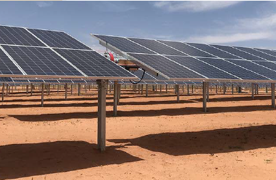 Na imagem são apresentadas várias placas solares vistas bem de perto. No chão de terra alaranjada, as sombras das placas se destacam