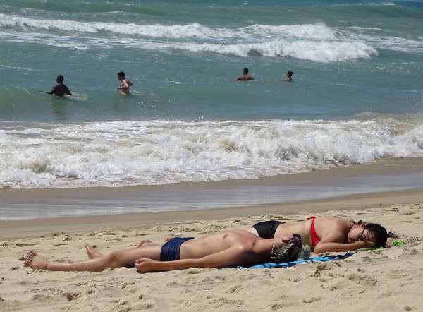 Banhistas tomam sol na areia da praias