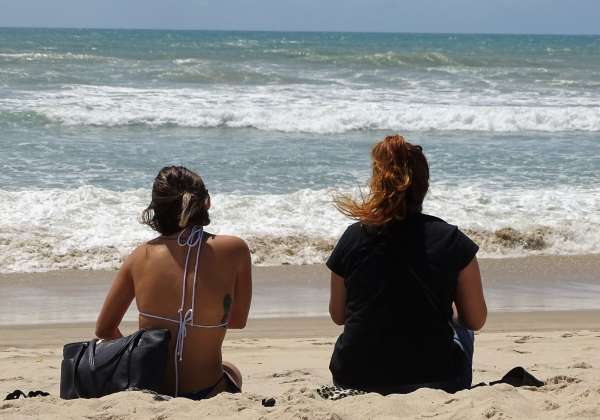 Duas banhistas na praia observam o mar