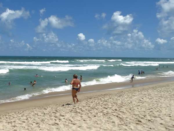 Banhista na praia caminha para o mar