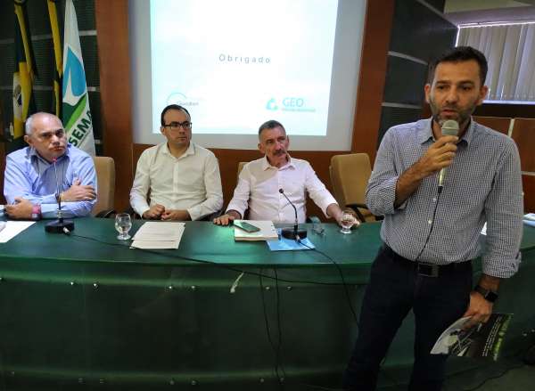 Representante da empresa interessada fala durante reunião do Coema e é observado pela mesa