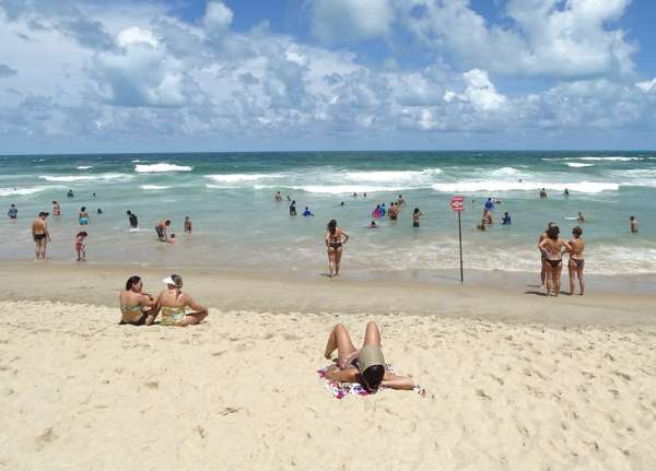 Praia com banhistas aproveitando o mar