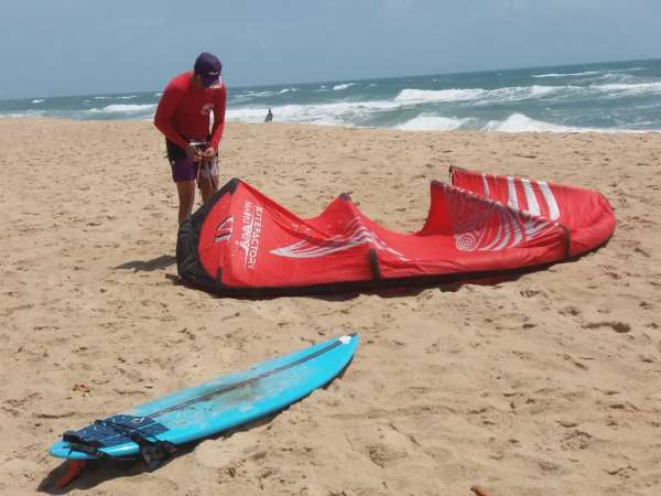 Kitesurfista ajusta vela na praia