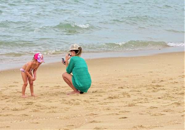 Mulher e criança brincam na areia da praia