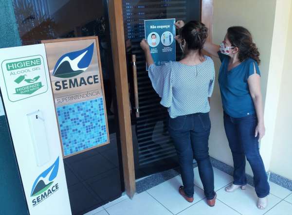 Funcionárias sinalizam prédio da Semace com cartaz